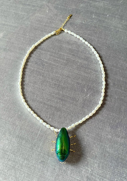 Resin coated beetle on beaded pearl necklace with gold clasp.