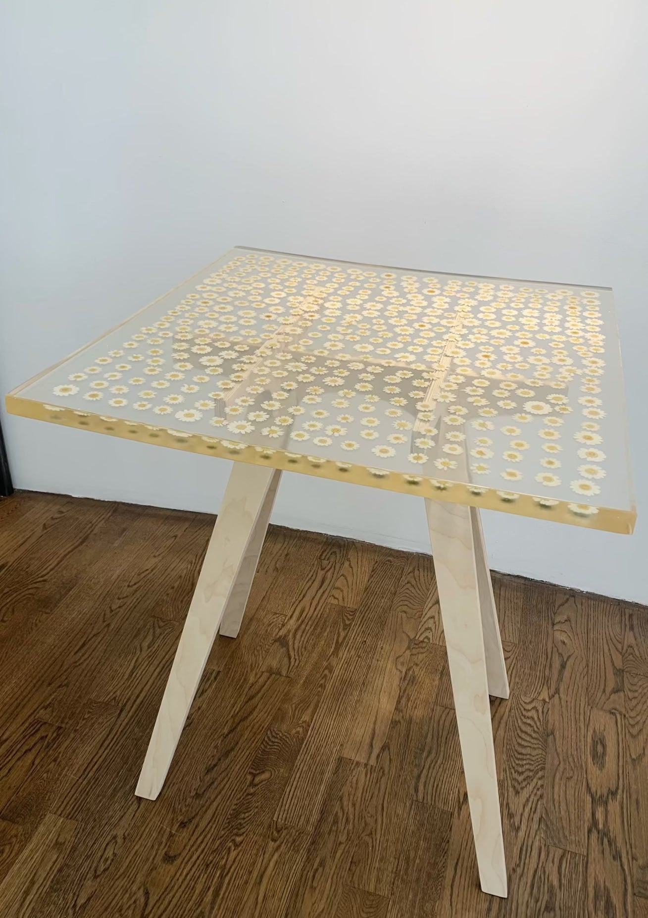a hand-poured resin cocktail or side table where hundreds of real daisies float atop a sturdy birch base.