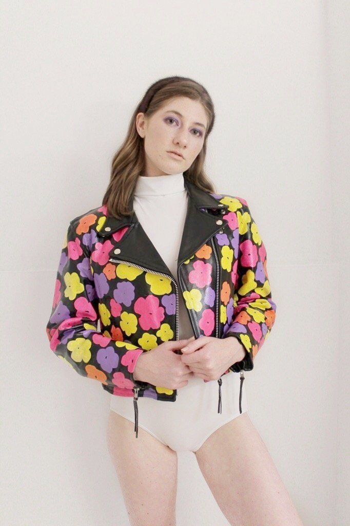 Black leather jacket hand-painted with pink, orange, and yellow 80s florals inspired by Andy Warhol's iconic pop art.