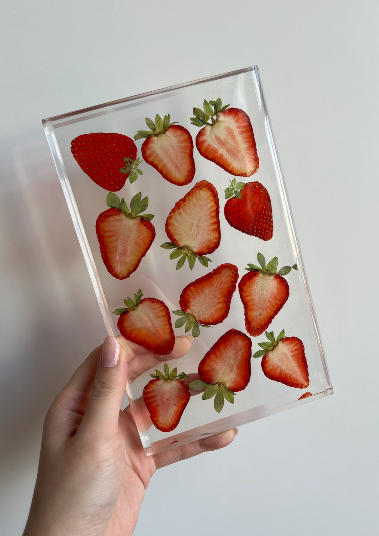 Strawberries sit suspended in a transparent resin tray. A durable-yet-whimsical addition to your home decor. Serve cocktails, use as a vanity tray, or simply display as an incredible objet d'art.