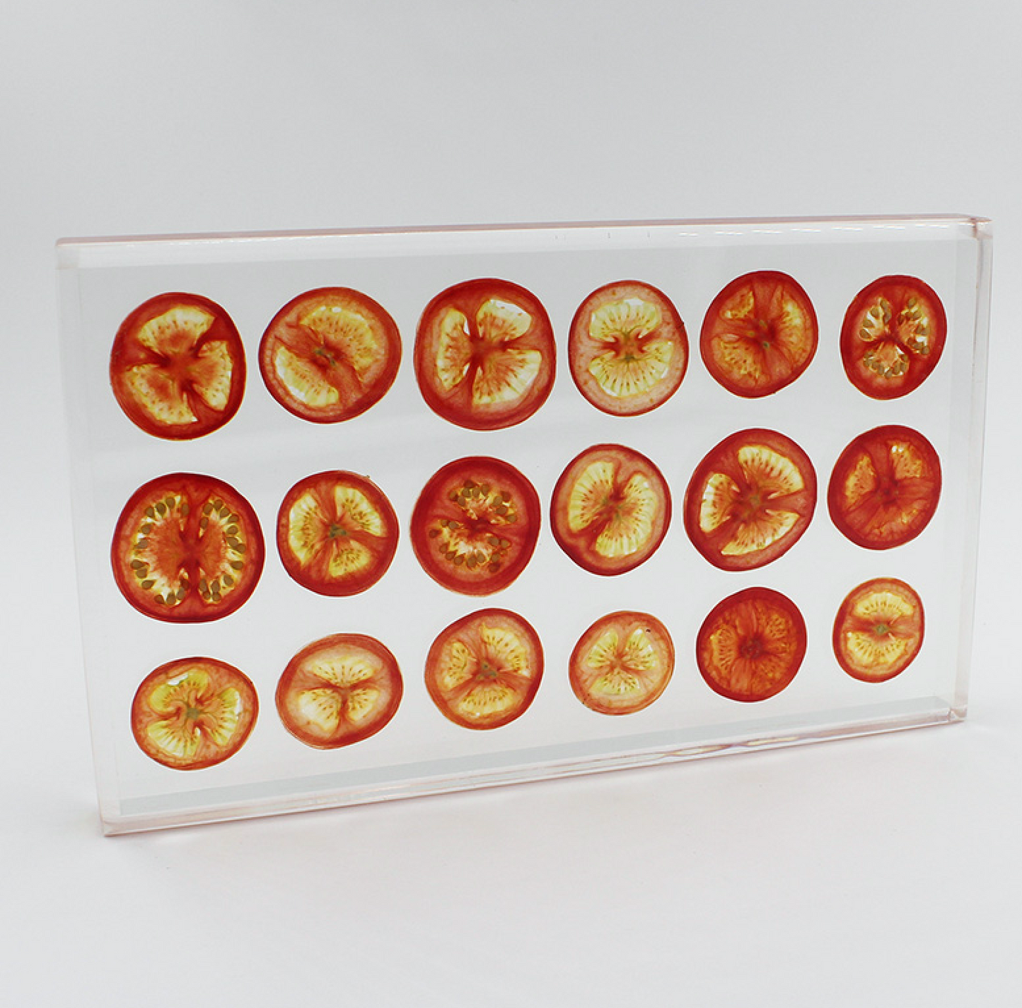 Tomatoes sit suspended in transparent resin tray