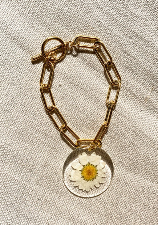 Daisy pendant on gold chain bracelet.