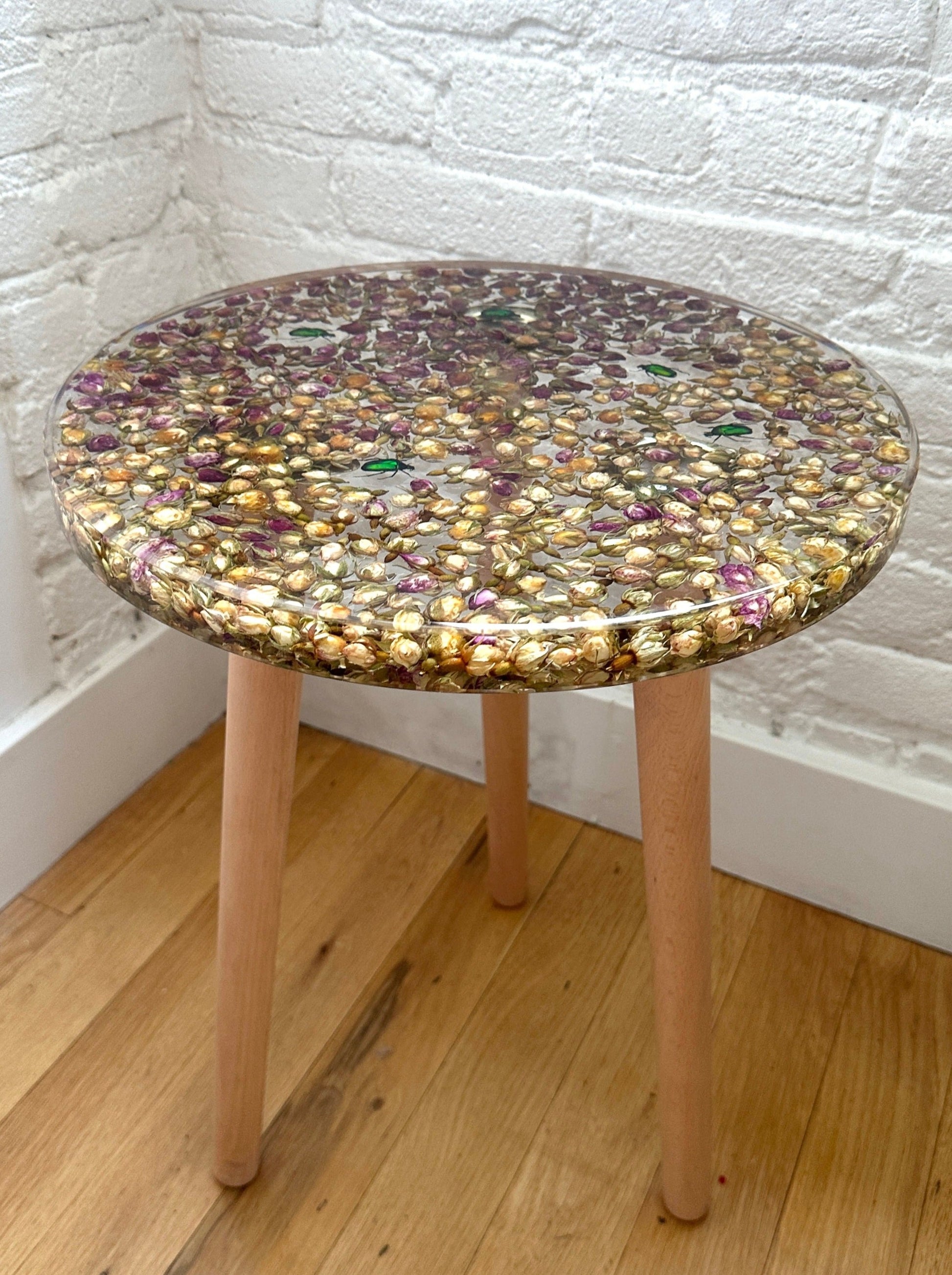 a hand-poured resin desk where hundreds of real rosebuds and beetles float atop three wooden legs.