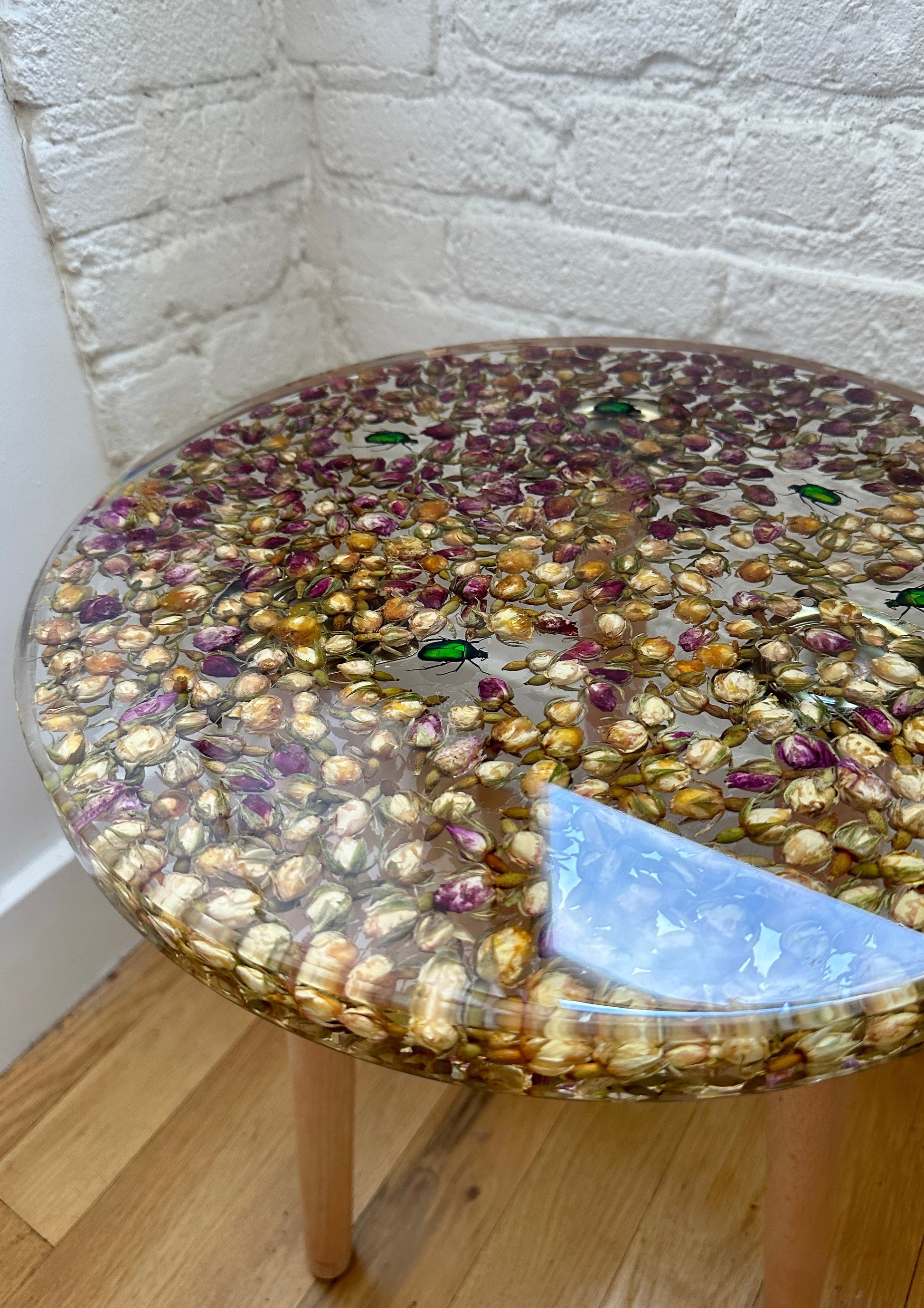 a hand-poured resin desk where hundreds of real rosebuds and beetles float atop three wooden legs.