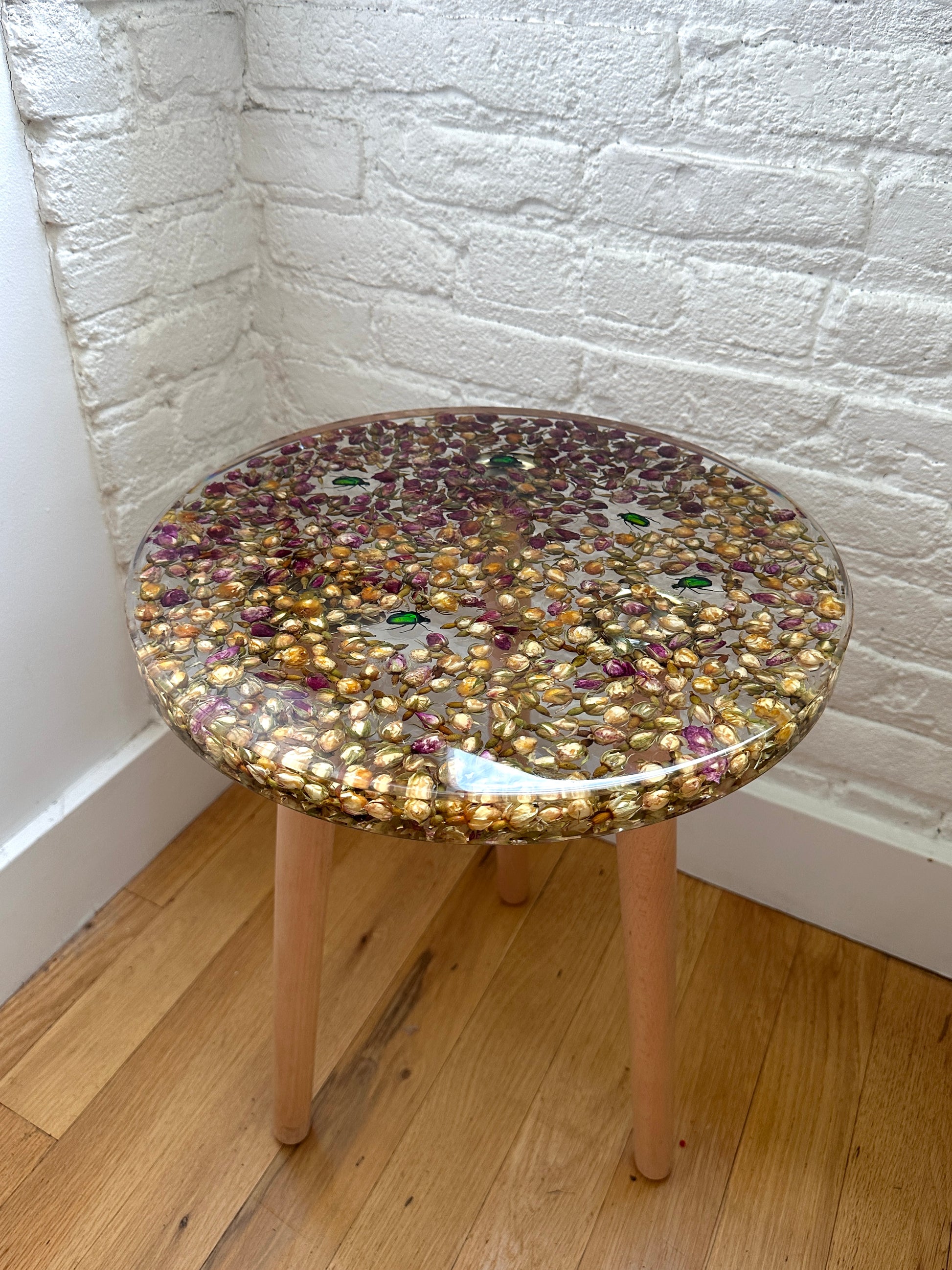 a hand-poured resin desk where hundreds of real rosebuds and beetles float atop three wooden legs.