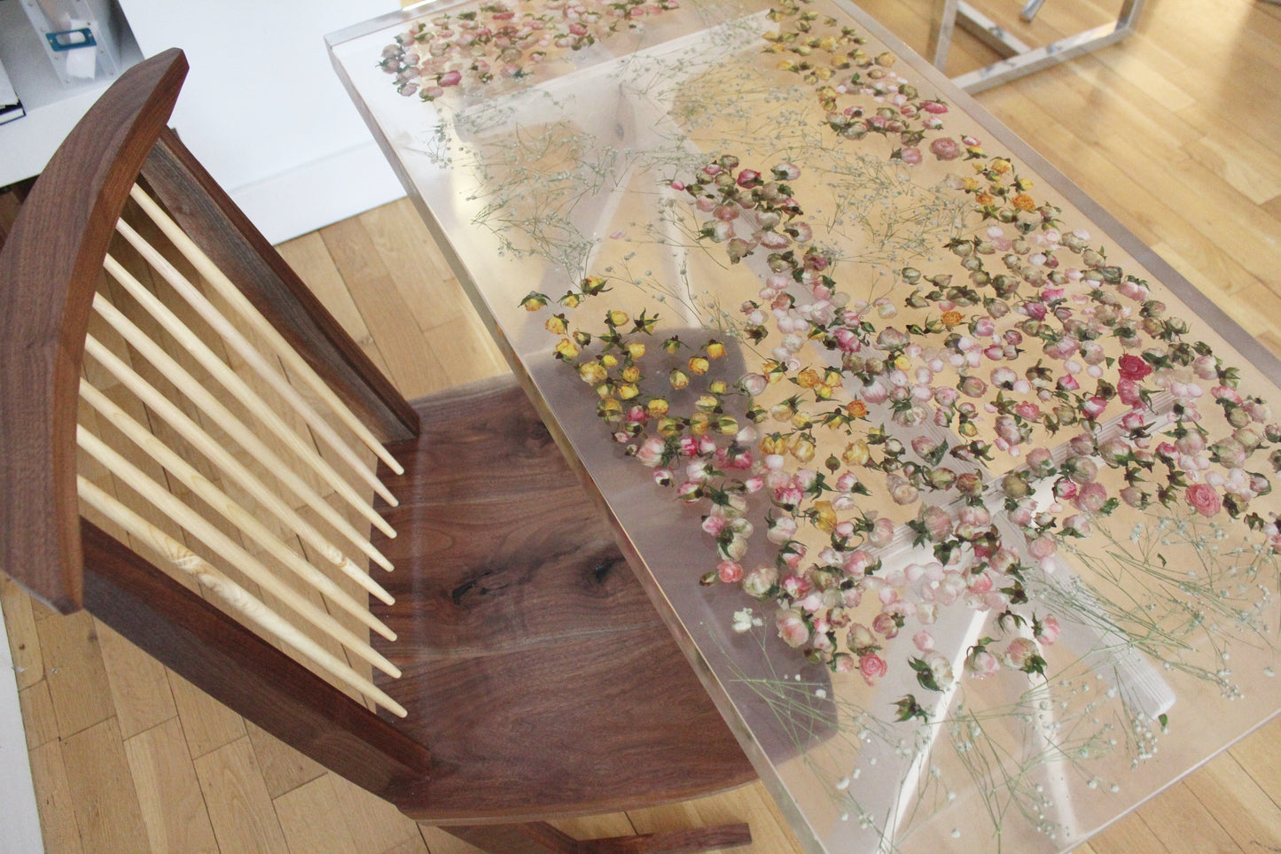 a hand-poured resin desk where hundreds of real rosebuds and baby's breath sprigs float atop a sturdy birch base