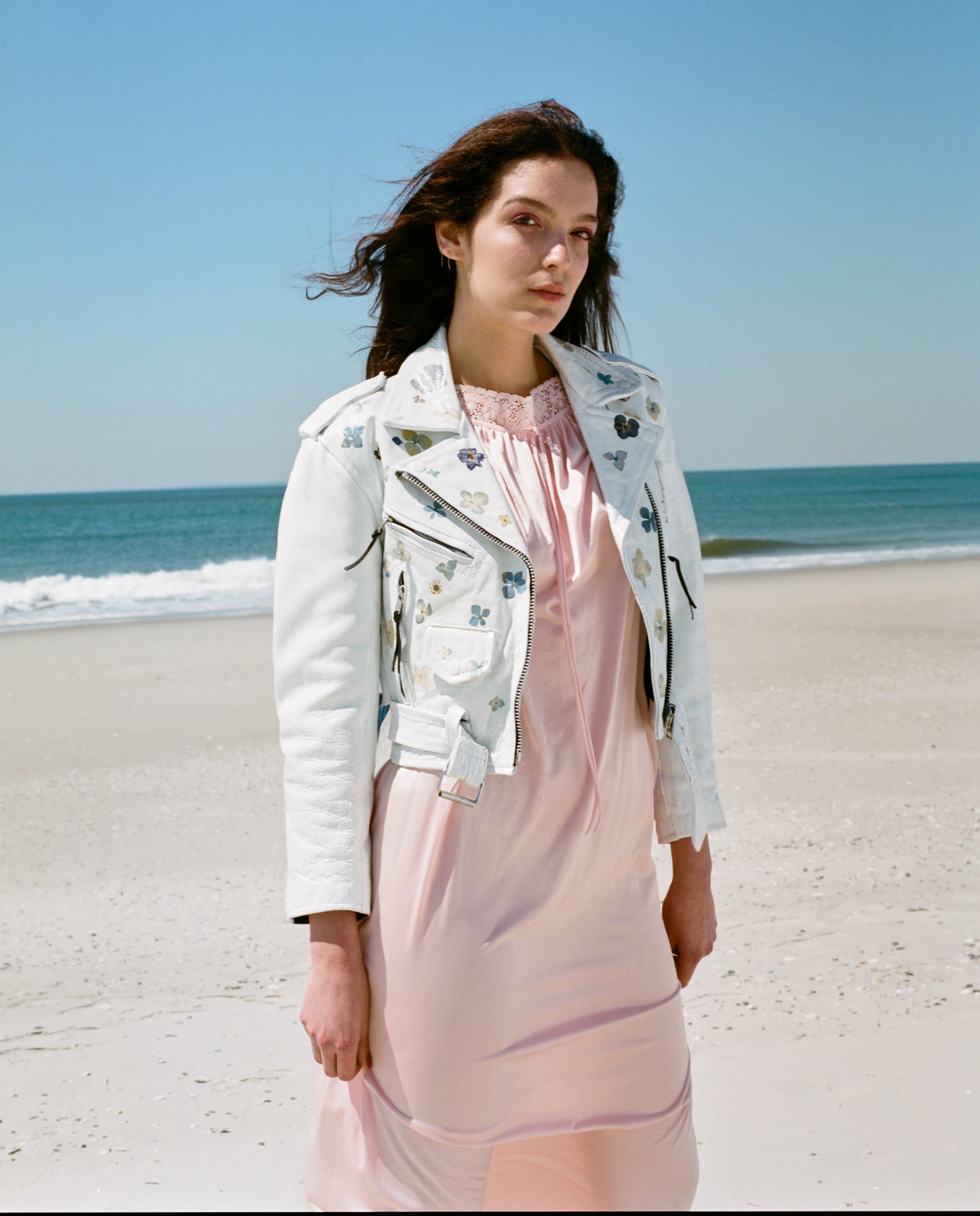 a vintage leather jacket coated in white paint, delicately adorned with real pressed flowers