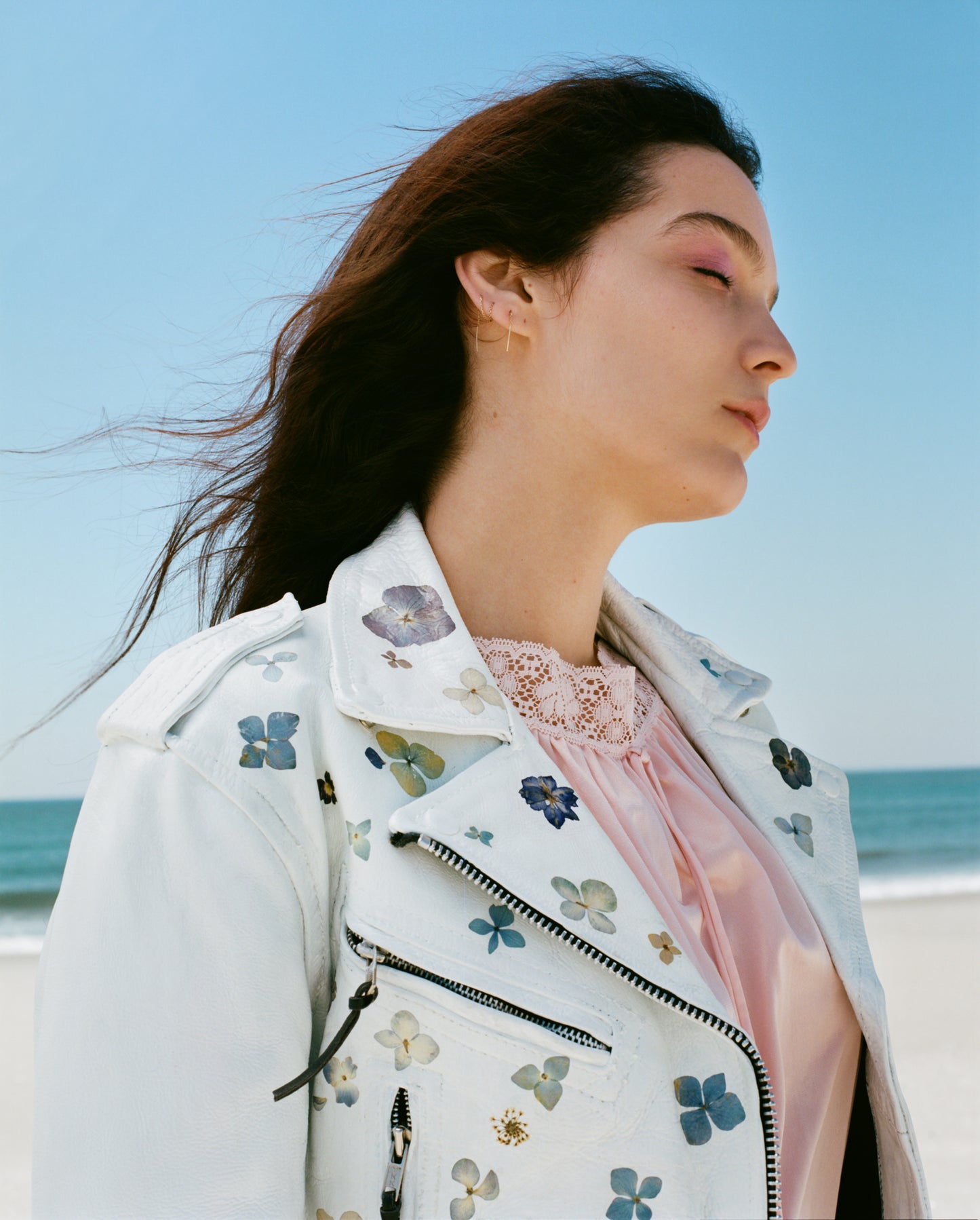 a vintage leather jacket coated in white paint, delicately adorned with real pressed flowers