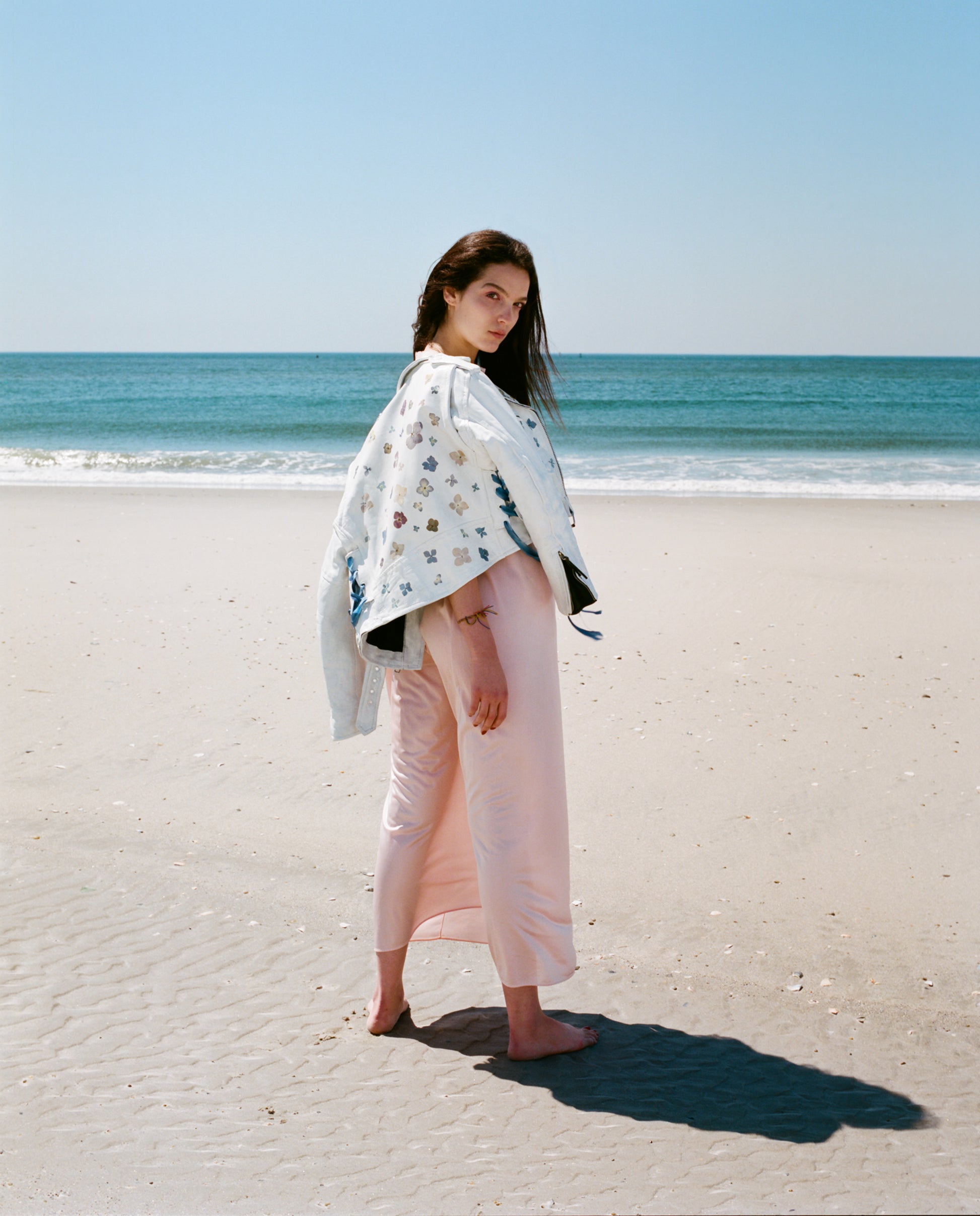 a vintage leather jacket coated in white paint, delicately adorned with real pressed flowers