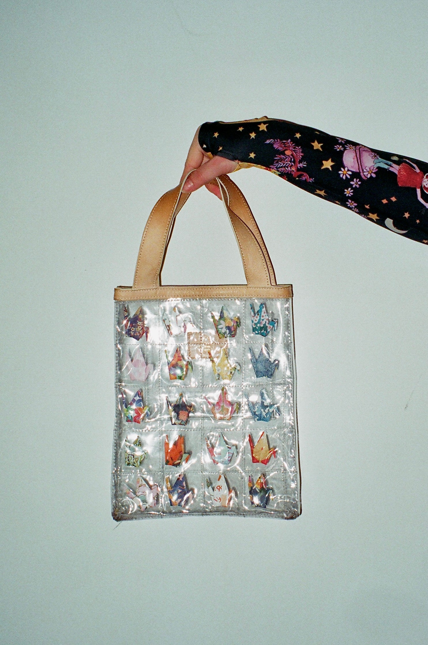 Clear quilted tote bag with mini paper cranes in each quilted square and cream straps.