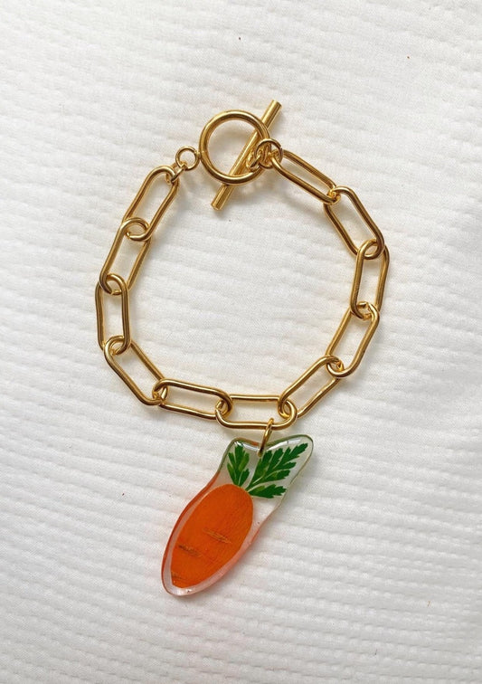 Tiny baby carrot slice suspended from a gold-plated stainless steel Albert chain.