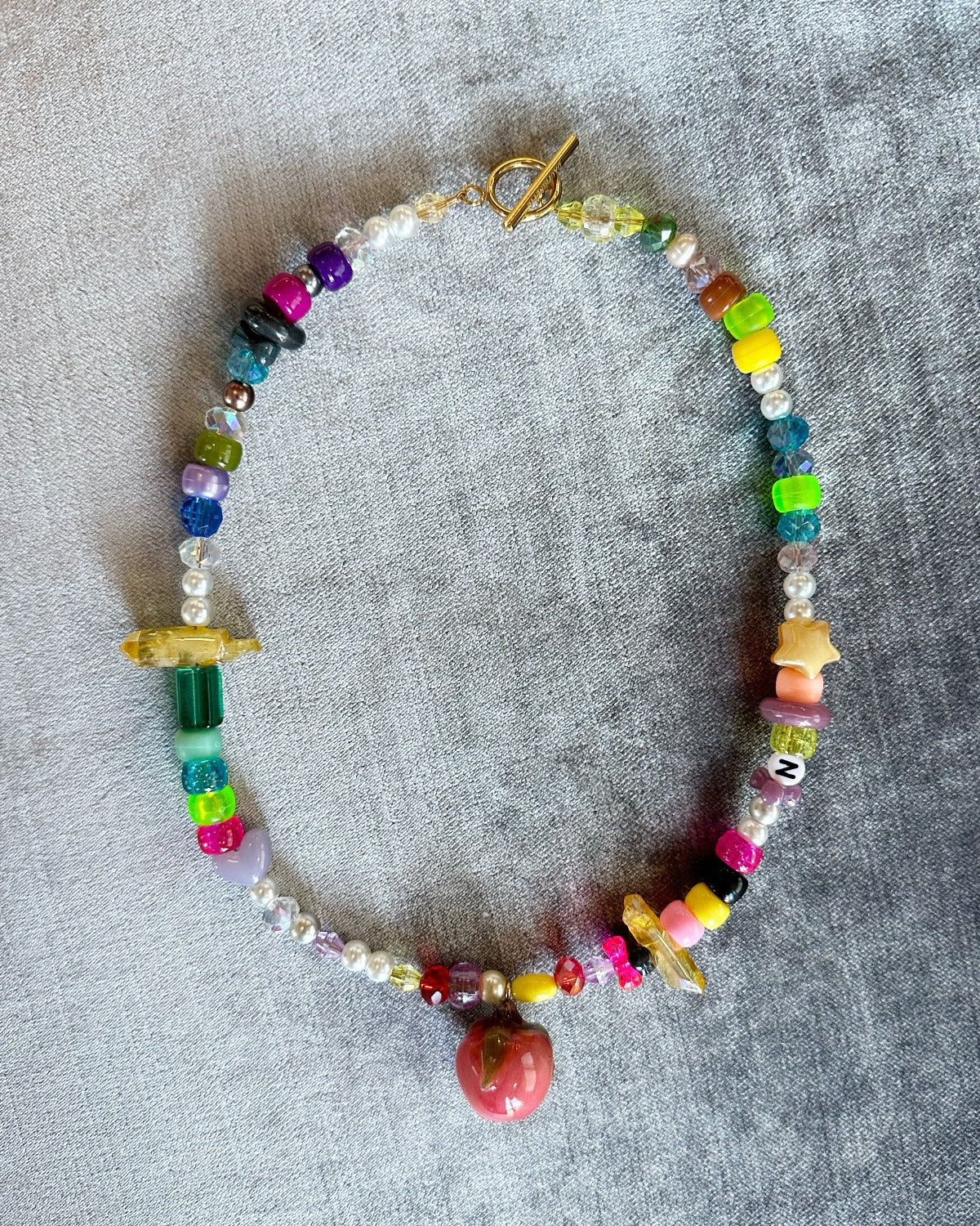 Assorted bead strand with resin fruit charm and gold clasp.