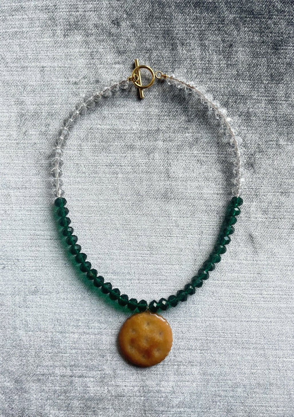 Resin dipped Ritz Cracker pendant on white and green beaded necklace with gold clasp.