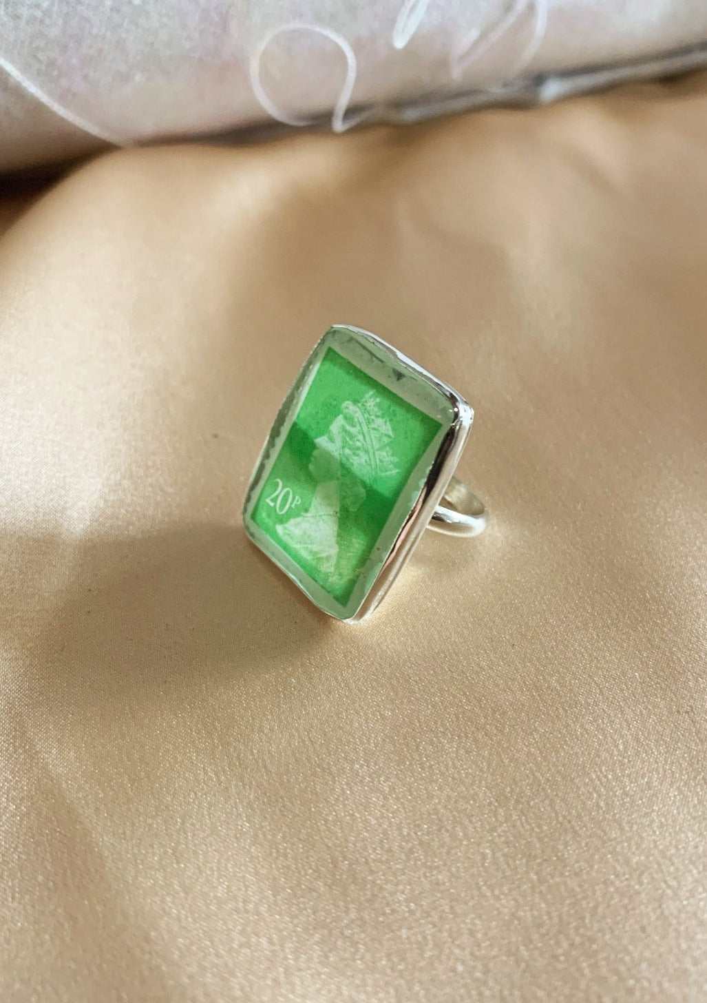 Green vintage stamp preserved in resin on silver ring band.