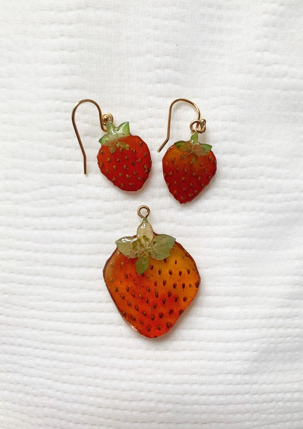 Two Miniature Strawberry earrings next to a regular Strawberry earring