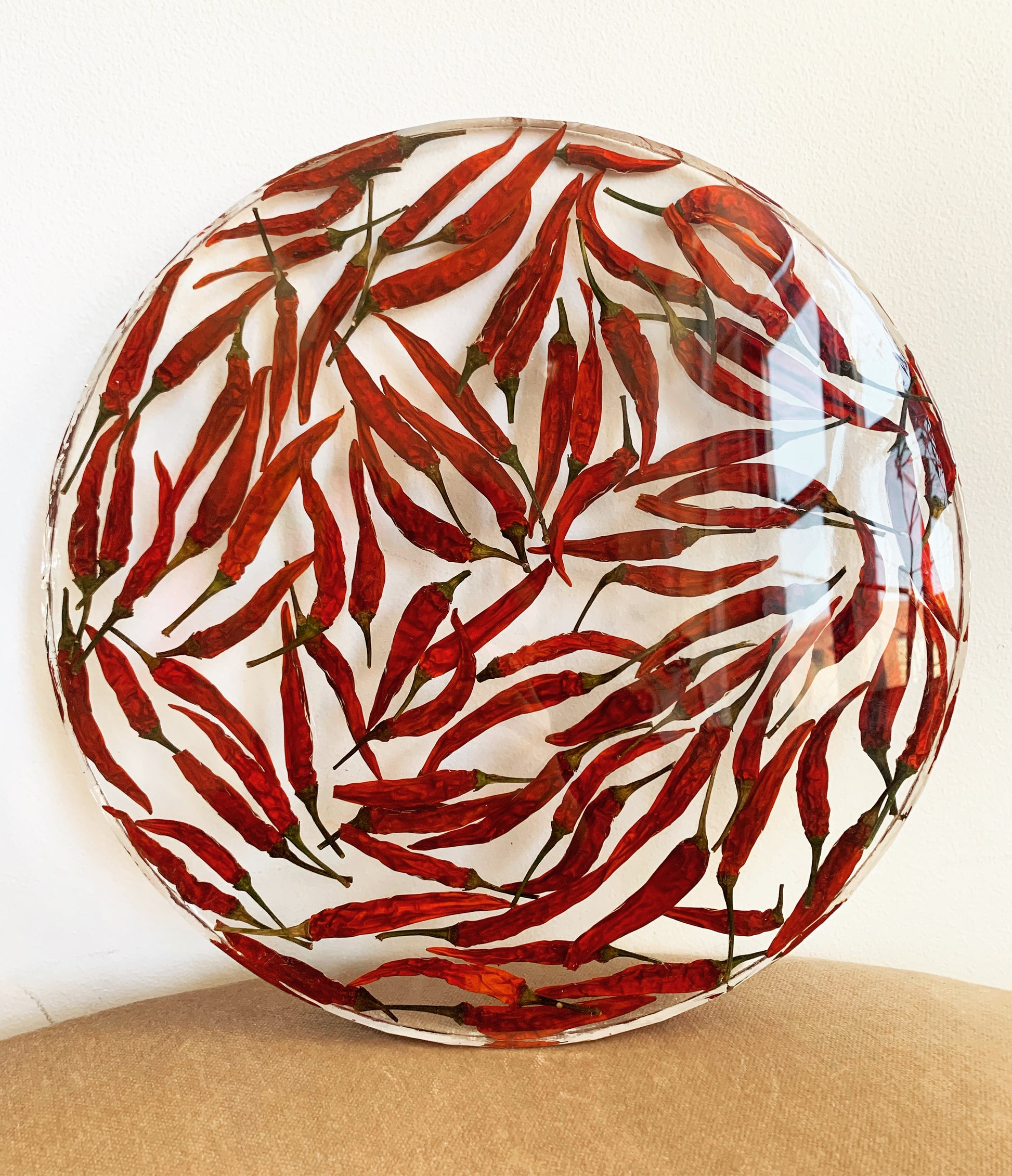 Dozens of peppers sit suspended in a round transparent resin. A durable-yet-whimsical addition to your home decor. Serve cocktails, use as a vanity tray, or simply display as an incredible objet d'art.