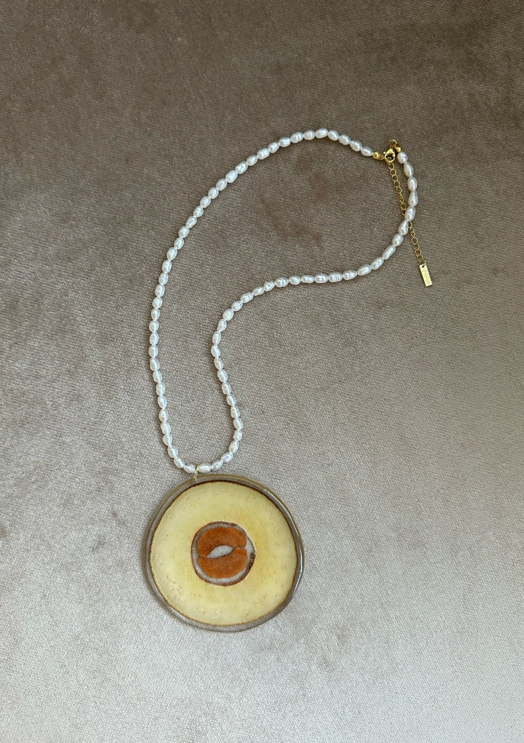 Freshwater rice pearl necklace with a preserved avocado cross-section pendant.