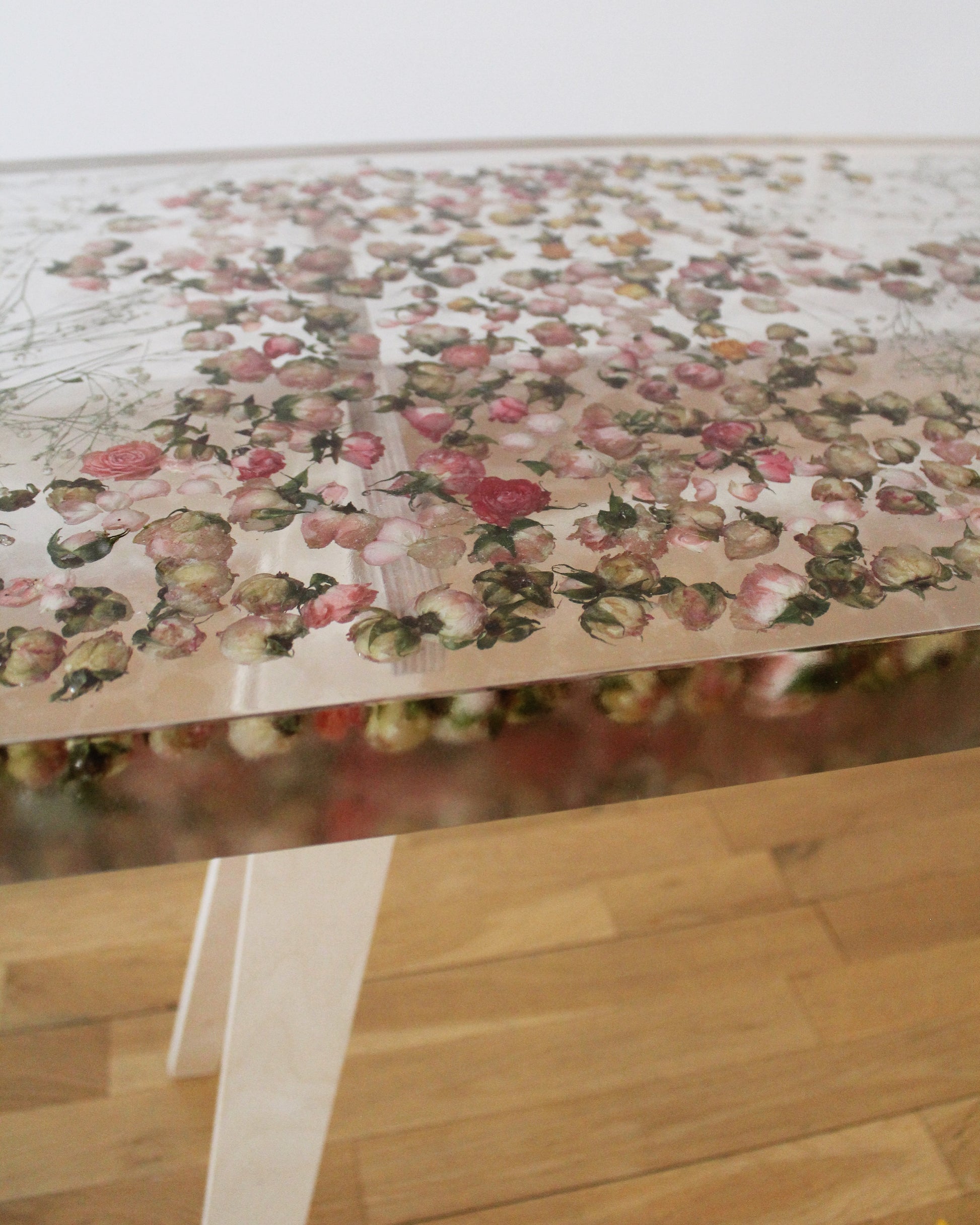 a hand-poured resin desk where hundreds of real rosebuds and baby's breath sprigs float atop a sturdy birch base