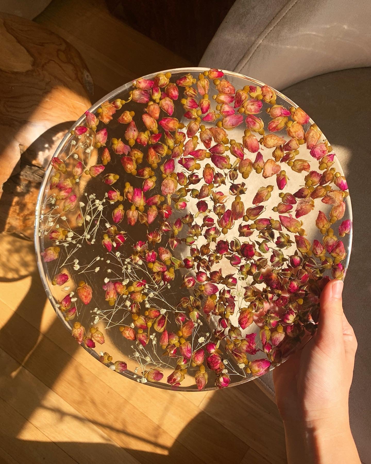  Hundreds of rosebuds sit suspended between sprigs of baby's breath. A durable-yet-whimsical addition to your home decor. Serve cocktails, use as a vanity tray, or simply display as an incredible objet d'art.  Approximately 12" diameter and 3/4" thickness.