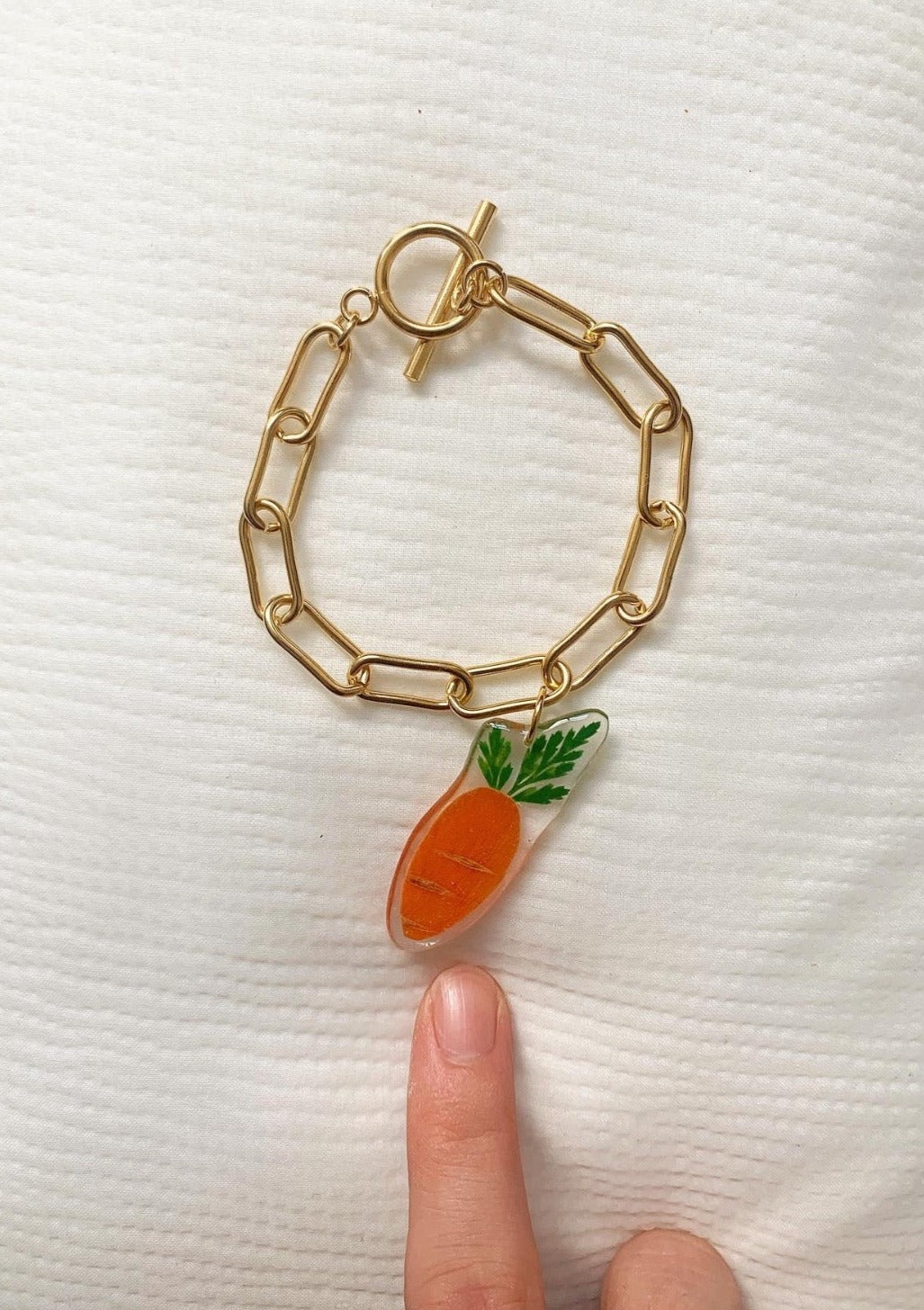 Tiny baby carrot slice suspended from a gold-plated stainless steel Albert chain.