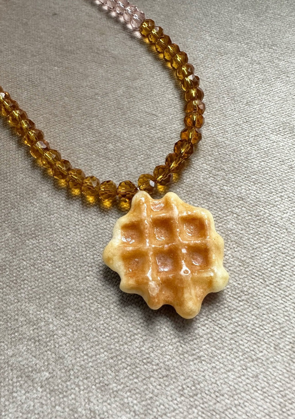 Real miniature waffle biscuit pendant preserved in resin on syrup and rose tone glass beaded chain with gold clasp.