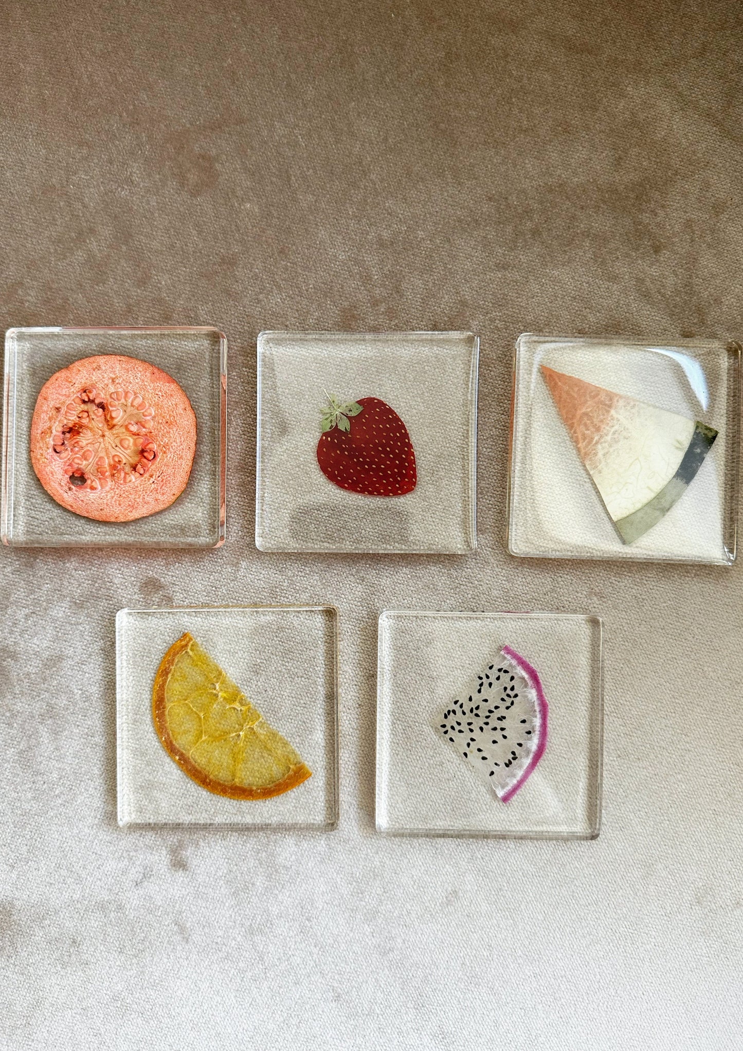 papaya, strawberry, watermelon, orange, and guava  each in a clear resin square coaster