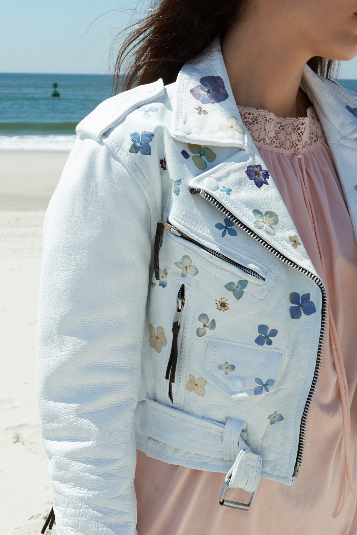 a vintage leather jacket coated in white paint, delicately adorned with real pressed flowers