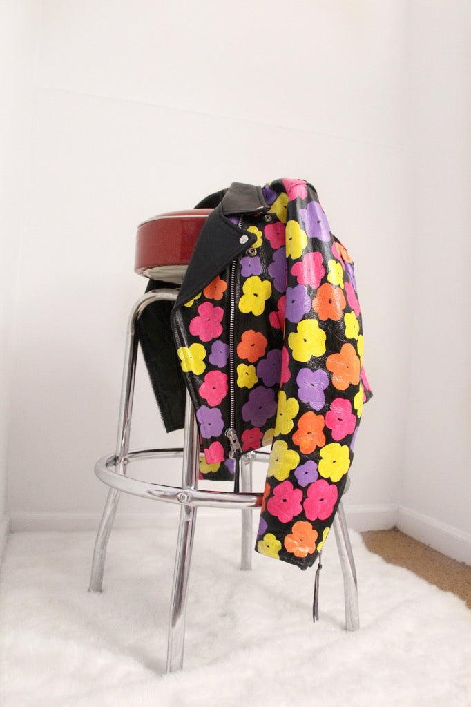 Black leather jacket hand-painted with pink, orange, and yellow 80s florals inspired by Andy Warhol's iconic pop art.