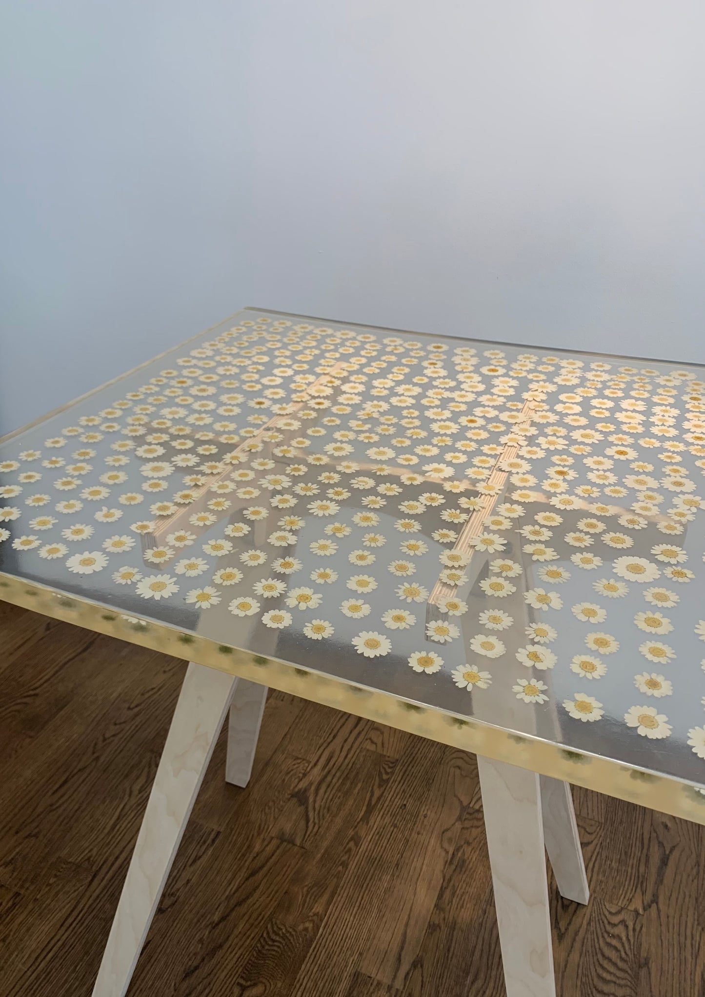 a hand-poured resin cocktail or side table where hundreds of real daisies float atop a sturdy birch base. 