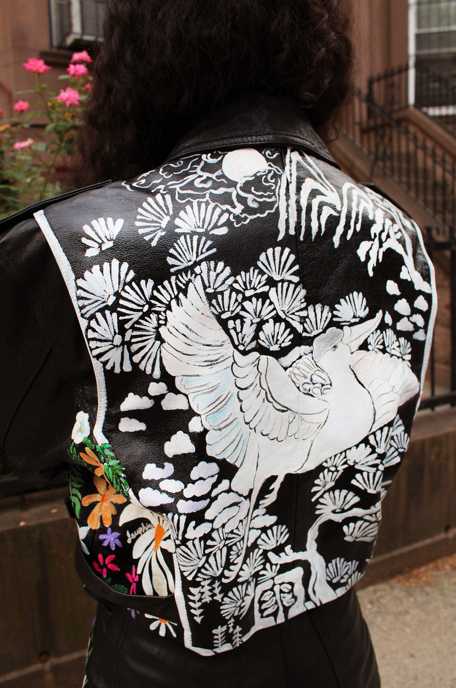 Fully hand-painted black motorcycle jacket dating from the 1980s. Floral scrapbook imagery to front, inspired by vintage pressed botanical prints. Pearl powder infused, crane-painted backside, modeled after antique mother-of-pearl inlaid cabinetry. Cropped style with silver hardware and adjustable belt