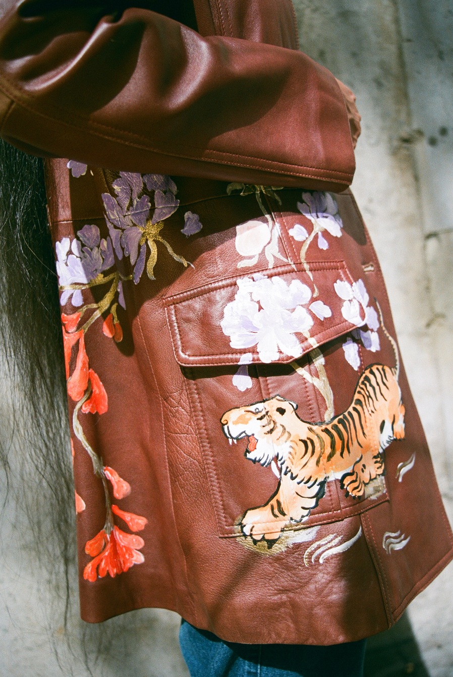 Hand-painted brown leather sportswear jacket from the 1980s. Tiger and floral motifs adapted from Chinese scroll paintings and cabinetry.