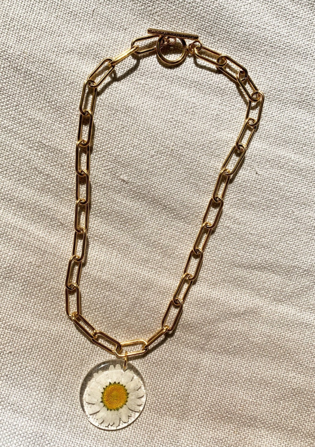 Resin coated daisy on chunky gold chain.