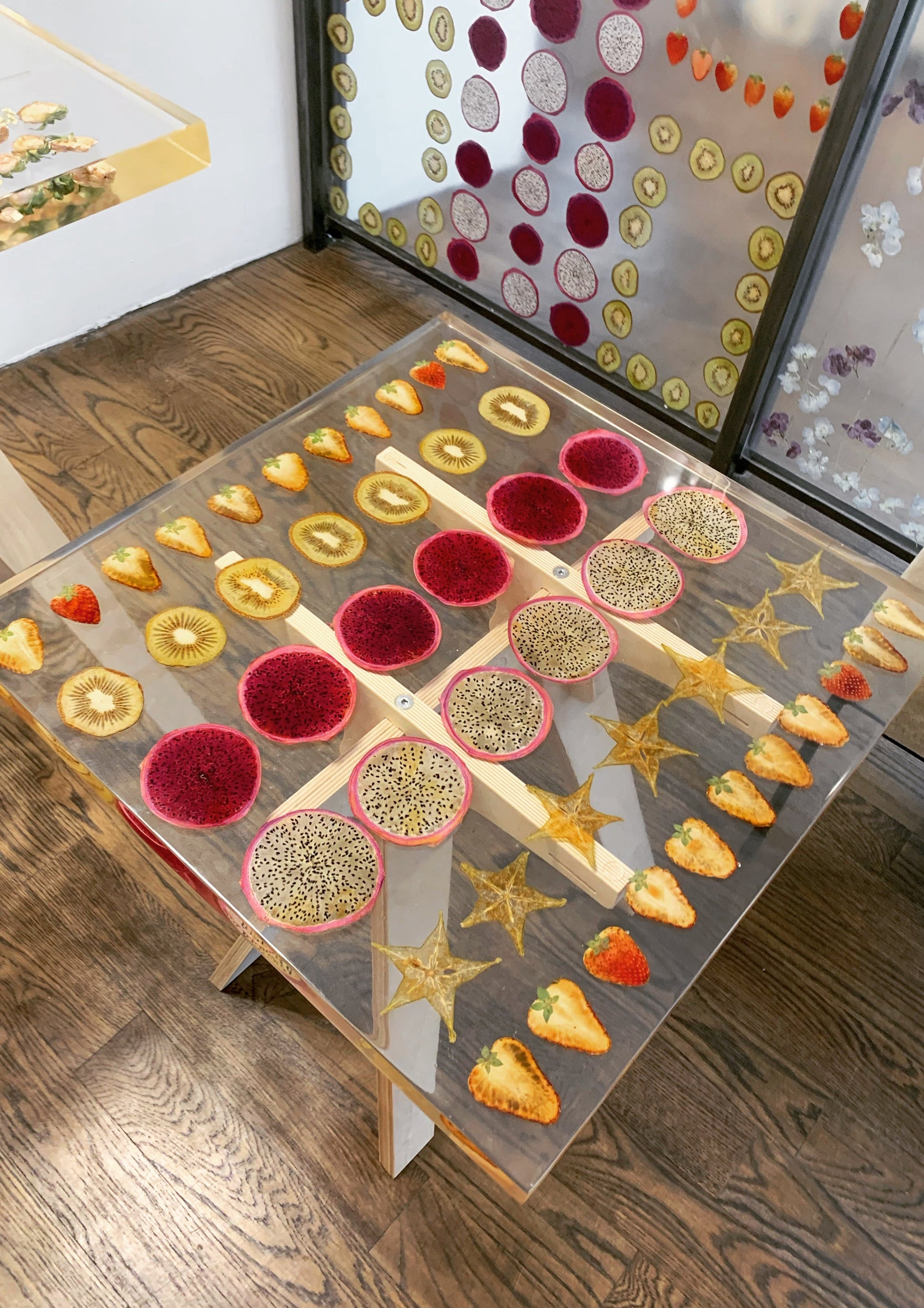 a hand-poured resin cocktail table where preserved strawberries, starfruit, kiwis, and dragonfruit float atop a sturdy birch base. 